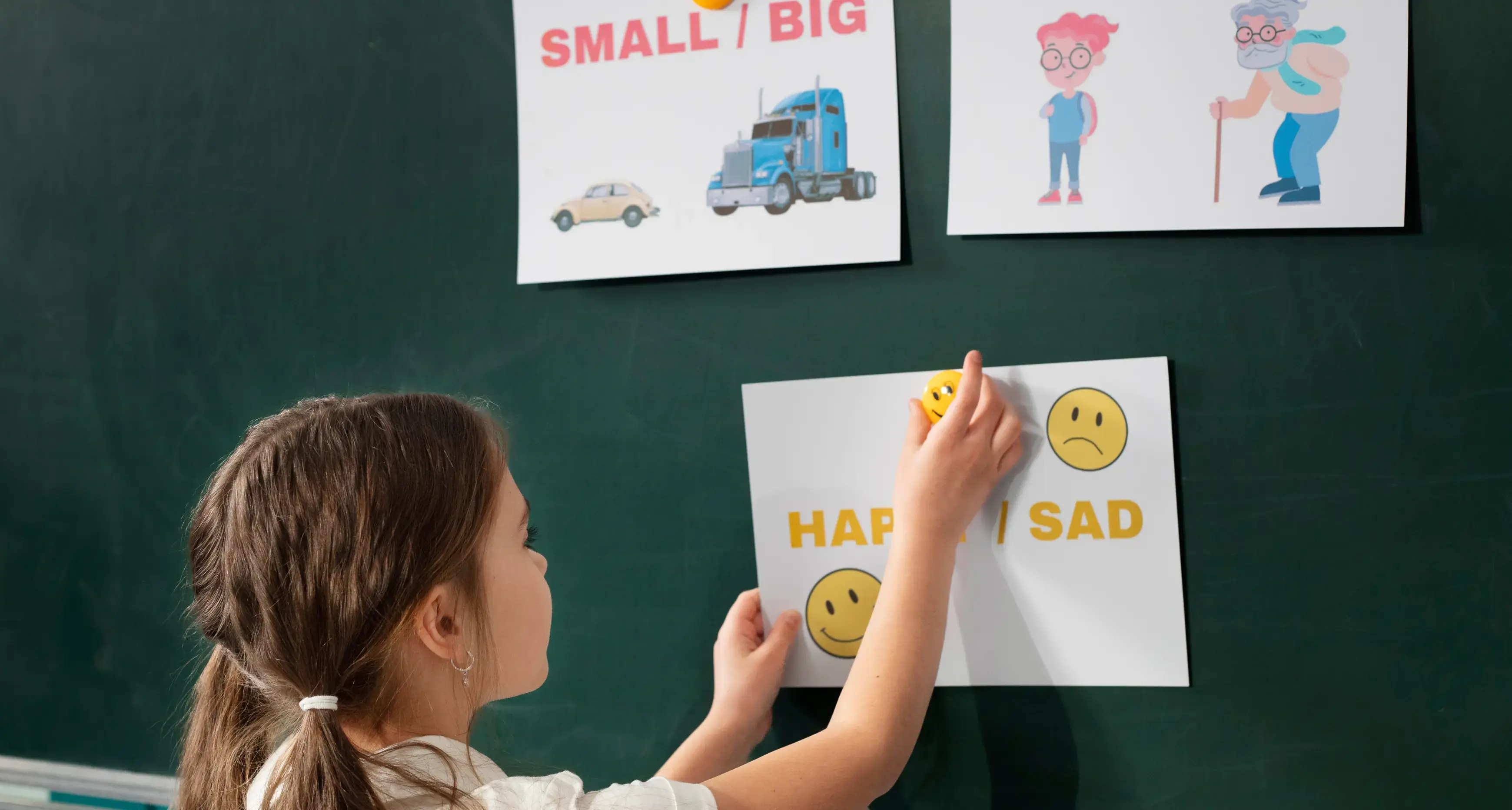 Niña poniendo comparativos y superlativos en inglés en un pizarrón